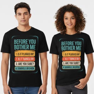 May include: Black t-shirts with the text "BEFORE YOU BOTHER ME" and a list of troubleshooting steps in a rectangular design. The shirts are worn by two people, one male and one female.