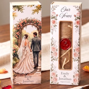 May include: Two rectangular wedding vow boxes featuring a watercolor illustration of a couple walking through a floral archway. The boxes are decorated with pink roses and include the text Our Vows, Emily & Jonathan, and August 24 2025.