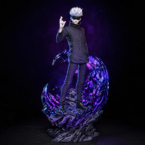 Op de afbeelding: Gedetailleerd beeldje van een personage met wit haar en een zonnebril, gekleed in een donkere jas en broek. Het beeldje staat op een paars-zwarte kristallijne basis, met een gloeiende paarse energiesfeer erachter. De achtergrond is donkerpaars.