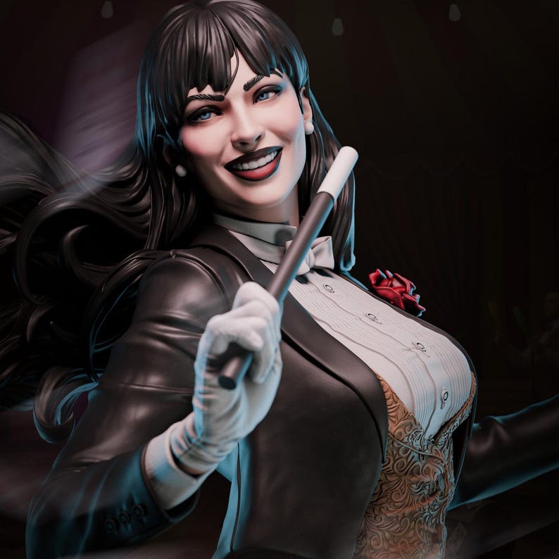 May include: A statue of a woman with long black hair, wearing a black suit jacket, white shirt, and a bow tie. She holds a magic wand and smiles. A red rose is pinned to her lapel. The statue has a detailed design and is set against a dark background.