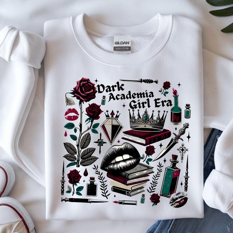 K&ouml;nnte beinhalten: Wei&szlig;es Sweatshirt mit einem Grafikdesign mit dem Text "Dark Academia Girl Era". Das Design umfasst Rosen, eine Krone, B&uuml;cher, einen Diamanten, Lippen und andere gotisch inspirierte Elemente in Rot, Schwarz und Gr&uuml;n.