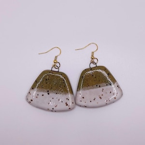 May include: A pair of green and white ceramic earrings with gold hooks. The earrings are speckled with white and brown flecks.