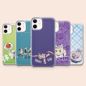 Pode incluir: Cinco capas para smartphone com ilustrações de personagens estilo anime. Os designs incluem uma capa verde com gráfico de comida, uma azul com três personagens, uma roxa com o texto Oguri Cap, uma capa de colagem roxa e uma xadrez azul.