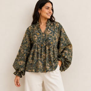 May include: A long-sleeved blouse featuring a dark olive green base with a repeating floral pattern in shades of tan, brown, and cream. The blouse has a ruffled collar, a V-neckline, and voluminous sleeves that gather at the wrists with ruffled cuffs.