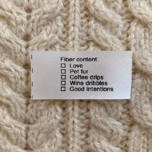 May include: White fabric label with black text that reads "Fiber content: Love, Pet fur, Coffee drips, Wine dribbles, Good intentions".