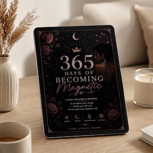 Puede incluir: Una tableta digital muestra un planificador diario y un diario titulado "365 Days of Becoming Magnetic". La portada es negra con detalles florales rosas, una luna creciente y el texto "Align, Attract, Become."