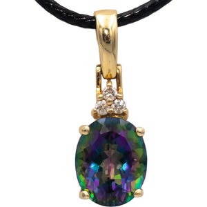 May include: Gold pendant with an oval, iridescent gemstone, suspended from a black cord. The pendant features a gold bail and a cluster of three small, clear gemstones above the main stone. The iridescent stone displays a range of colors.