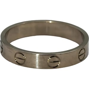 May include: A silver-toned metal band ring featuring a smooth, polished finish. The exterior surface of the ring is decorated with evenly spaced, circular engravings that resemble screw heads, each containing a single horizontal line detail.