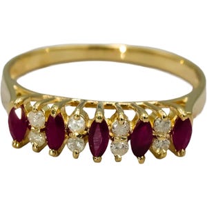 May include: A yellow gold ring featuring an alternating row of four marquise-cut deep red rubies and three pairs of small round white diamonds. The stones are set in a prong setting along the front half of the polished gold band.