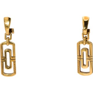 May include: A pair of gold-toned earrings. Each earring features a rectangular, open-frame design with an inner, stylized 'C' shape. The word 'BVLGARI' is inscribed on the lower portion of each earring. The earrings have a hinged top for attachment.