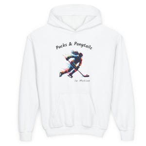 Puede incluir: Sudadera con capucha blanca con un gr&aacute;fico frontal. El gr&aacute;fico presenta una ilustraci&oacute;n colorida de una jugadora de hockey en movimiento, con el texto "Pucks & Ponytails" y "In Motion".