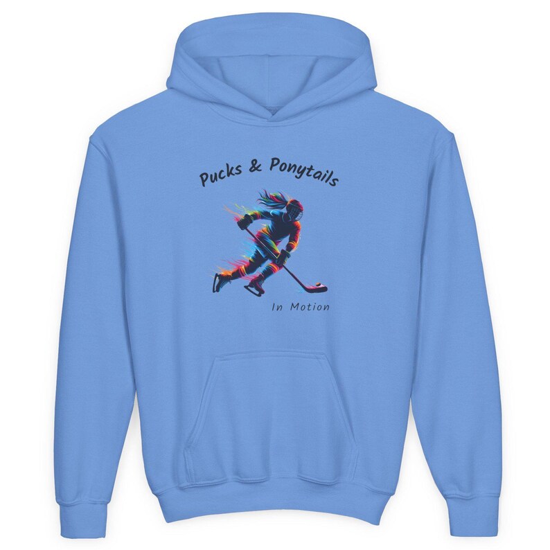 Puede incluir: Sudadera con capucha azul claro con bolsillo delantero y capucha con cord&oacute;n. La sudadera presenta el texto "Pucks & Ponytails" encima de un gr&aacute;fico colorido de un jugador de hockey en movimiento. Las palabras "In Motion" est&aacute;n debajo.