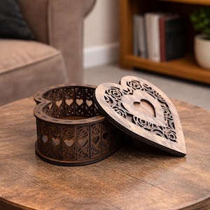 May include: A wooden heart-shaped box with an open lid. The box and lid are brown with intricate cut-out designs of hearts and floral patterns. The box sits on a wooden table.