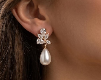 Könnte beinhalten: Elegante Ohrhänger mit einem Cluster aus klaren Kristallen und einer tropfenförmigen Kunstperle. Die Ohrringe sind goldfarben und für formelle Anlässe konzipiert. Die Ohrringe sind etwa 5 cm lang.