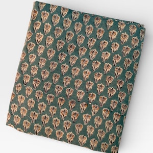 A neatly folded rectangular piece of teal blue fabric with a repeating pattern of light brown and white floral motifs is centered on a white background.
