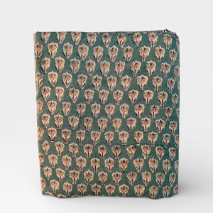 A rectangular block of teal blue fabric with a repeating pattern of light brown and white floral motifs is standing upright on a white background.