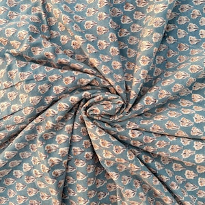 A teal blue cotton fabric with light brown and white floral motifs, swirled into a circular pattern.
