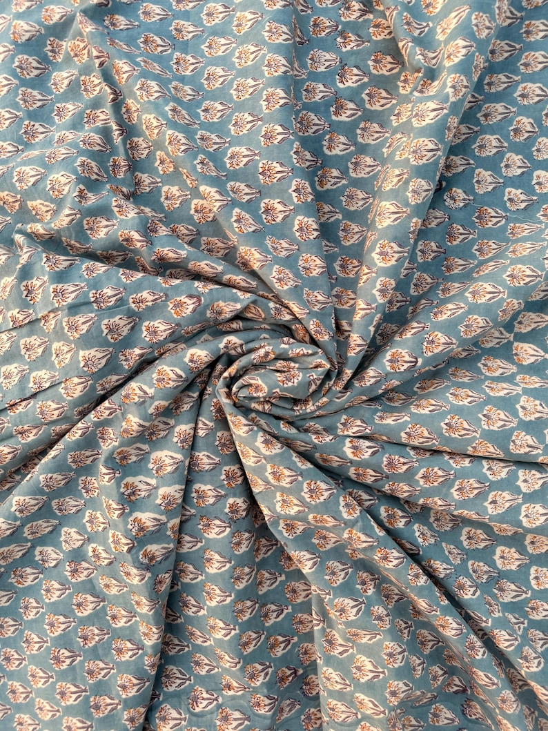 A teal blue cotton fabric with light brown and white floral motifs, swirled into a circular pattern.