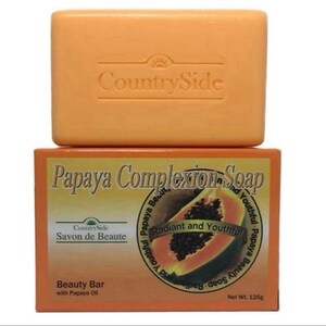 May include: An orange bar of CountrySide soap sits atop a box of Papaya Complexion Soap. The box features a papaya illustration and text that reads "Radiant and Youthful." The soap bar is labeled "Beauty Bar" and weighs 125g.
