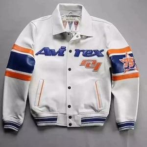 Puede incluir: Chaqueta de cuero blanca con detalles en azul y naranja. Presenta el texto "Avirex" en azul y el n&uacute;mero "75" en la manga. La chaqueta tiene un estilo bomber cl&aacute;sico con cierre de botones y pu&ntilde;os a rayas.