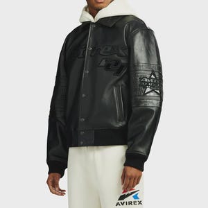 May include: A black leather varsity jacket featuring a snap-button front closure, a ribbed hem, and cuffs. The chest displays embossed Avirex branding, while the sleeves feature textured panels and a star graphic with the text All American.