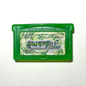 May include: A green Game Boy Advance cartridge featuring the game "Pokémon LeafGreen." The label includes the Nintendo logo, Japanese text, and the Pokémon Company branding. The cartridge has a green plastic shell.