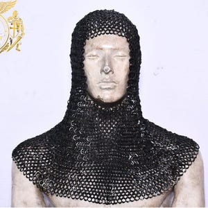 Peut inclure: Coiffe en cotte de mailles noire, une coiffe médiévale, présentée sur un mannequin. La coiffe est faite de petits anneaux métalliques imbriqués, offrant une protection pour la nuque et la tête. Le fond est blanc.