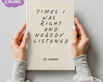 Könnte beinhalten: Ein cremefarbenes Buch mit dem Text "TIMES I WAS RIGHT AND NOBODY LISTENED" in schwarzer Handschrift. Das Buch wird von zwei Händen gehalten, und der Name des Autors, "BY. HANNA", steht unten. Eine lila Blase mit den Worten "MORE COLORS" befindet sich in der oberen linken Ecke.