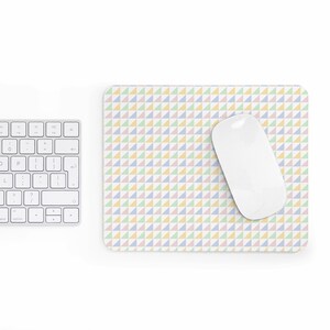 May include: A rectangular mousepad with a pastel triangle pattern in pink, blue, yellow, and green. A white computer mouse rests on the pad, next to a white keyboard.