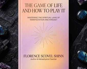 Può includere: Un libro con copertina rigida intitolato The Game of Life and How to Play It di Florence Scovel Shinn. La copertina presenta una sfumatura tenue color pesca e lavanda con un grafico centrale a stella e testo nero con il titolo.