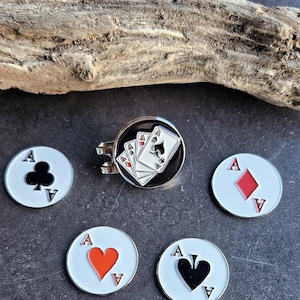 May include: Poker-themed accessories, including a silver-toned tie clip featuring a hand of cards and four white, circular tokens. Each token displays a different suit: clubs, diamonds, hearts, and spades. The cards and tokens have red and black accents.