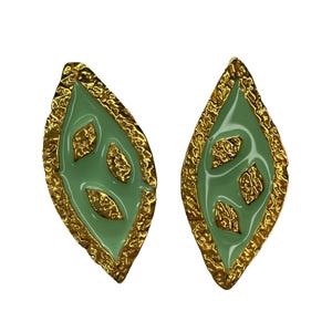 May include: A pair of leaf-shaped earrings. Each earring features a light green enamel center with gold-colored accents. The edges have a textured gold-colored border. The earrings are set against a white background.