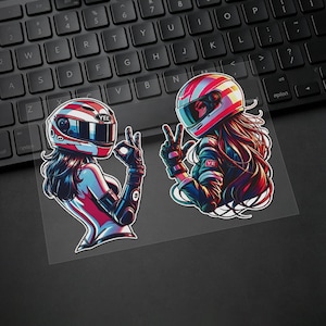 May include: Two die-cut stickers featuring stylised figures wearing racing helmets with red, white, and blue stripes. One figure makes an okay hand gesture, the other a peace sign. The helmets display the text YEE and YE on a black keyboard background.