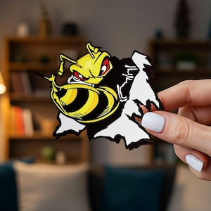 May include: A die-cut sticker featuring a stylized yellow and black wasp with red eyes, depicted as if bursting through a white paper surface with jagged, torn edges. The design uses bold black outlines and high-contrast colors for a graphic effect.