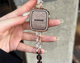 May include: Rose gold smartwatch with a decorative band featuring star-shaped accents. The watch face is surrounded by a border of small crystals. The watch displays the time 17:00 and the word "ROROPIE".
