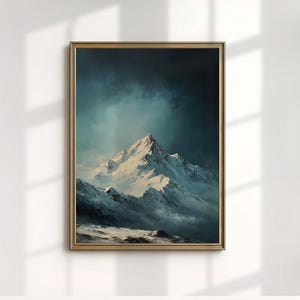 Puede incluir: Una impresión artística enmarcada que presenta una cordillera nevada bajo un cielo nublado y dramático. La obra de arte está realizada en tonos blancos, azules y grises, con un marco dorado. La imagen evoca una sensación de lo sublime y la belleza natural.