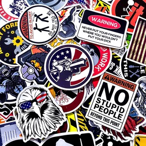 Op de afbeelding: Een verzameling diverse stickers met verschillende ontwerpen en tekst. De stickers tonen waarschuwingen, illustraties van een adelaar met zonnebril, een bouwvakker en een gewichtheffer. Sommige stickers hebben tekst zoals "No Stupid People Beyond This Point."
