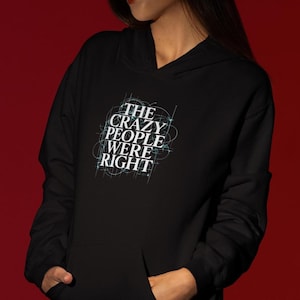 May include: Black hooded sweatshirt with a front pocket and the text "THE CRAZY PEOPLE WERE RIGHT" in white and light blue. The text is surrounded by a white and light blue design.