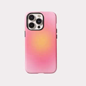 Op de afbeelding: Een smartphonehoesje met een vloeiend kleurverloop dat overgaat van felroze aan de randen naar een zachtgeel midden. Het hoesje heeft een zwarte uitsparing voor de camera met drie ronde lensopeningen en een kleine opening voor de flitser.
