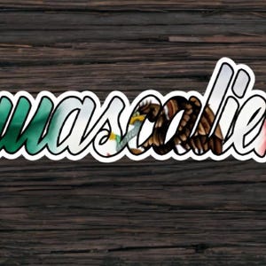 May include: A sticker featuring the word "Aguascalientes" in a decorative font. The letters are shaded in the colours of the Mexican flag: green, white, and red. The background is a dark wood grain.