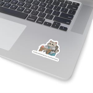 May include: A sticker featuring a cartoon cat in a business suit working at a desk with a laptop and coffee cup. The sticker has the text "actively monitoring your unsolved tickets" in a white font.