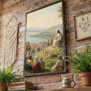 Puede incluir: Una impresión enmarcada de una escena religiosa, que muestra una figura con túnica blanca dirigiéndose a una multitud. La obra de arte se exhibe en una pared de ladrillo junto con otras obras de arte enmarcadas y objetos decorativos, incluyendo un tapiz de macramé y plantas en macetas.