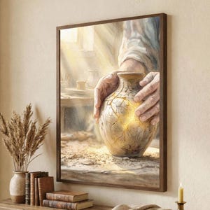 Peut inclure: Une impression encadrée à l'aquarelle représente un vase fissuré et vieilli tenu par des mains. Les fissures sont remplies de lumière dorée. L'œuvre est exposée sur une table en bois avec des livres, un vase de plantes séchées et une bougie allumée.