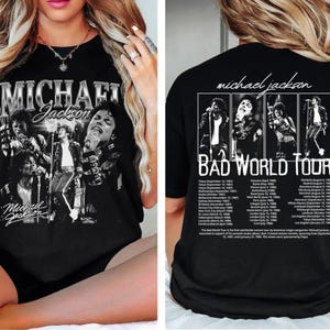 May include: Black t-shirt featuring a grayscale image of Michael Jackson with the text "MICHAEL Jackson" on the front. The back of the shirt displays "michael jackson" and "BAD WORLD TOUR" with tour dates and locations.