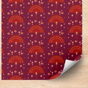 May include: A patterned sheet featuring a repeating design of red fans, lanterns, and small pink flowers on a deep burgundy background. The fans have gold accents and tassels. The sheet is partially rolled up, revealing a wooden surface.