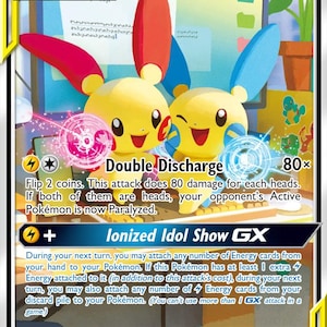 May include: A Plusle & Minun GX Tag Team trading card with 220 HP. The card features the two yellow creatures with red and blue ears, performing Double Discharge and Ionized Idol Show GX attacks. The background shows a computer desk setup.