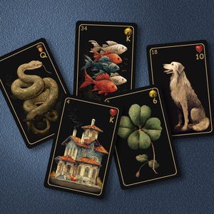 May include: Five rectangular playing cards with black backgrounds and gold borders. The cards feature illustrations of a coiled snake, three colorful fish, a white dog, a multi-story house, and a four-leaf clover, each with unique numbers and symbols.