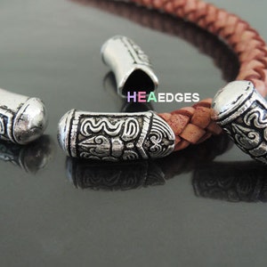 May include: Three silver metal end caps with an ornate design. The end caps are for leather cord or bracelet making.