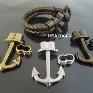 May include: Three anchor-shaped metal clasps for bracelets or necklaces. The clasps are in gold, silver, and bronze. Each clasp has a ring for attaching to a chain or cord.