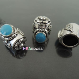 Puede incluir: Tres terminales de cordón de metal plateado con diseños ornamentados. Dos de los terminales tienen una piedra azul turquesa en el centro. Los terminales son para un cordón de cuero.